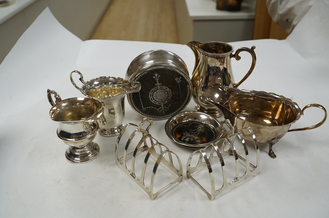 Sundry small silver including a pair of toast racks, Sheffield, 1936, three cream jugs, a sauceboat and two tortoiseshell mounted items. Condition - poor to fair to good